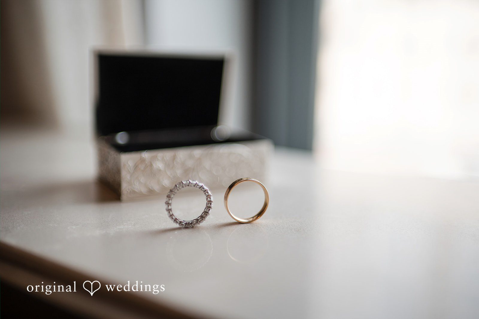 Close-up of two wedding bands resting next to an open ring box.