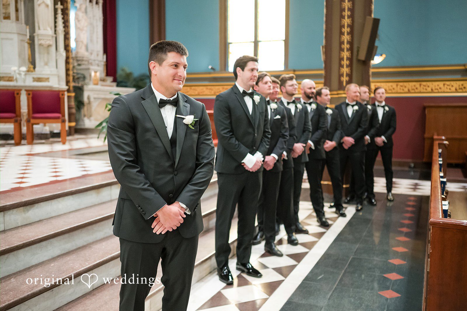 Groom standing at the front of a church with groomsmen lined up behind him.