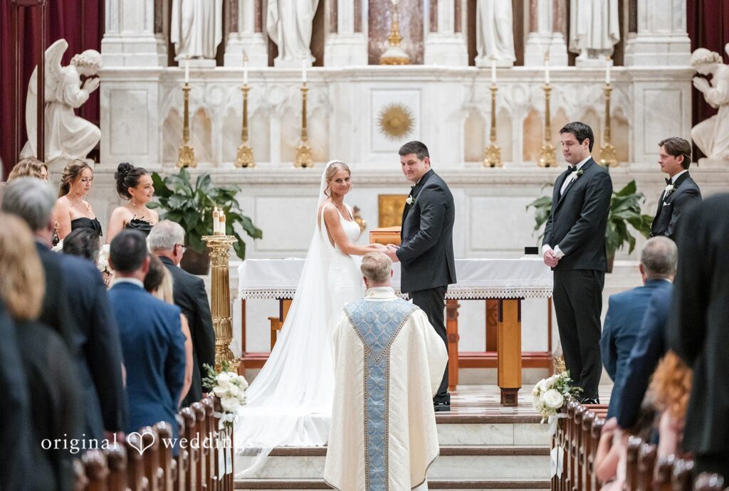 Wedding ceremony facing the altar with a priest standing before the bride and groom.