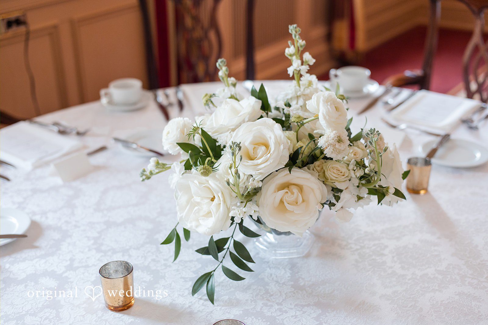 White floral centerpiece arranged on a draped banquet table.