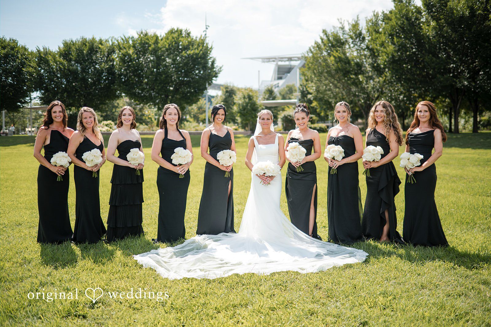 Bride and bridesmaids in dark dresses surrounding a seated bride.