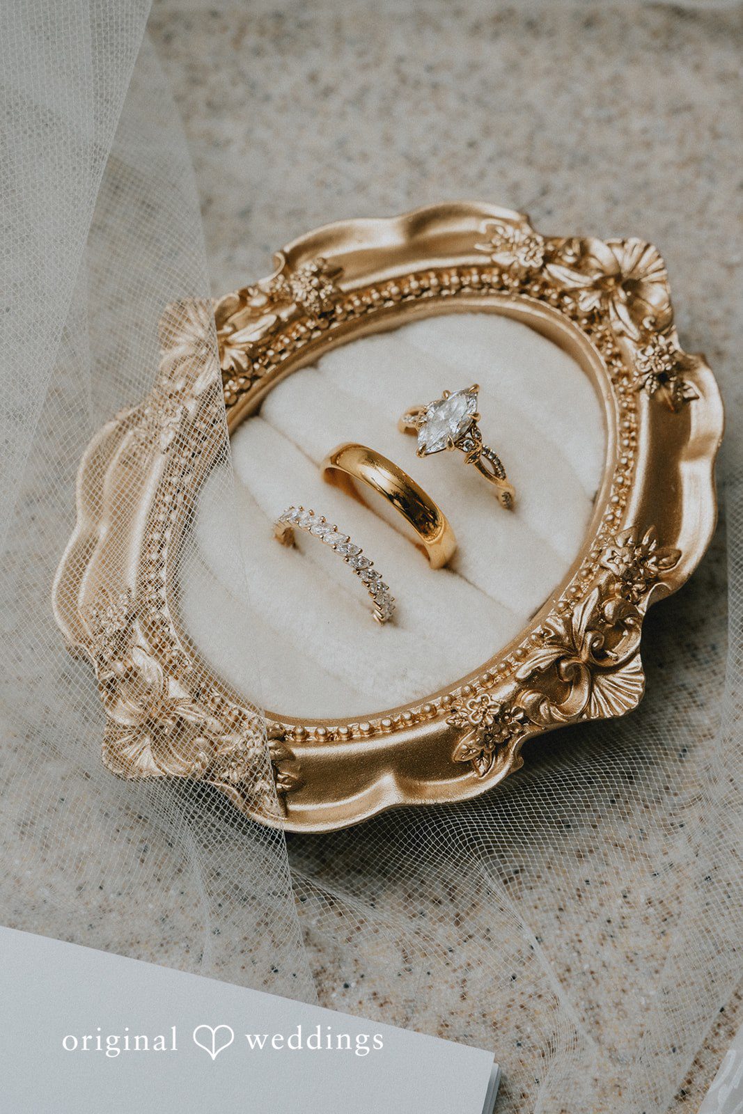 Carly + Dillon Two gold wedding rings resting inside a decorative vintage gold tray.