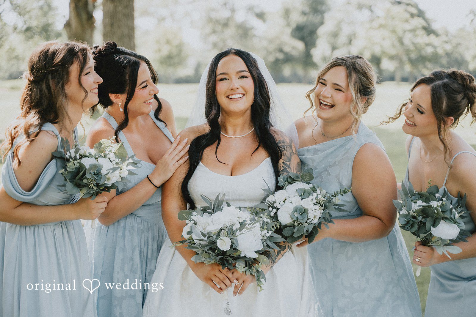 Carly + Dillon A laughing bride standing closely with her bridesmaids during a photo session.