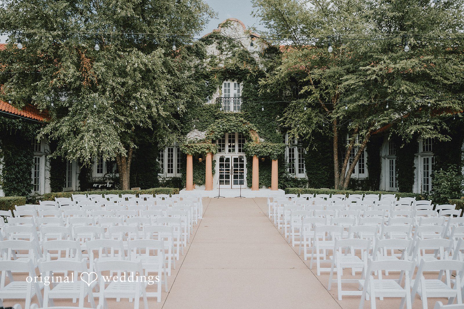 Carly + Dillon An empty wedding ceremony venue with rows of white chairs facing an altar.