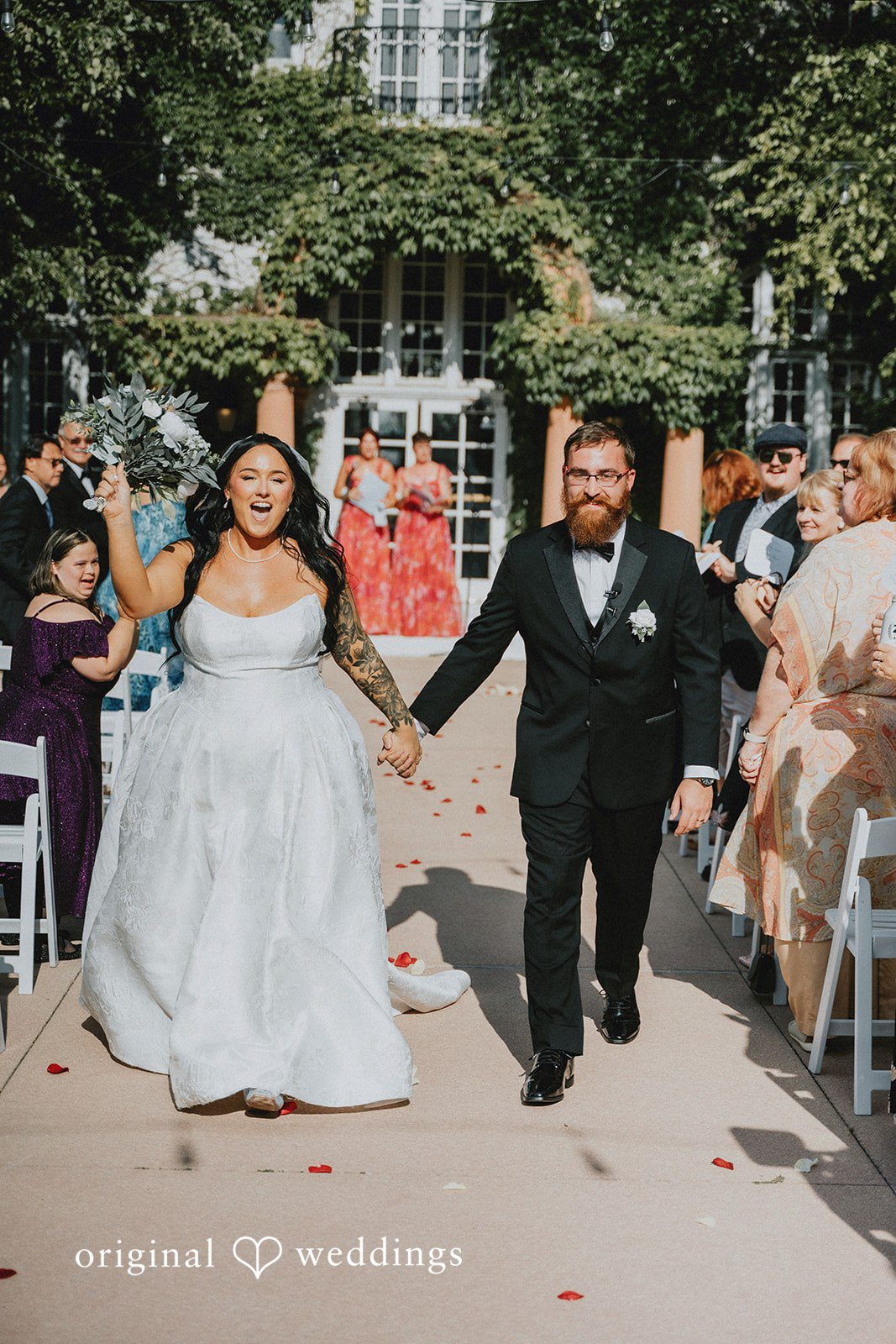 Carly + Dillon A newly married bride and groom smiling while walking down the aisle together.