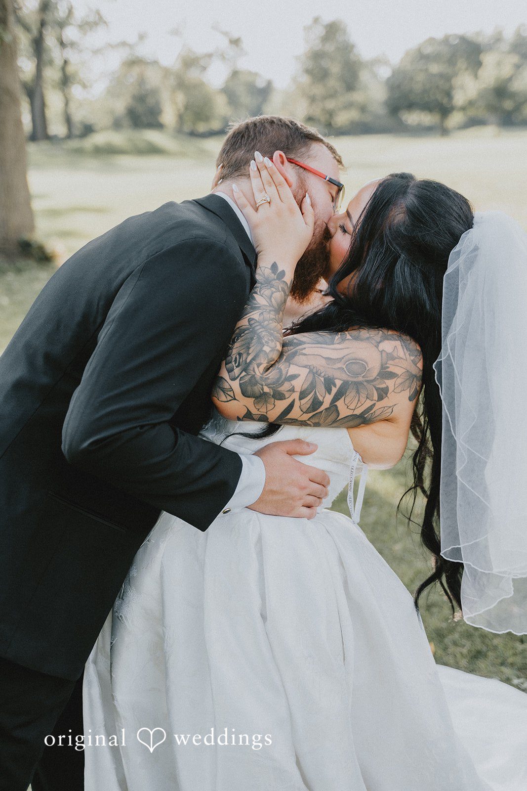 Carly + Dillon A groom leaning down to passionately kiss his bride.