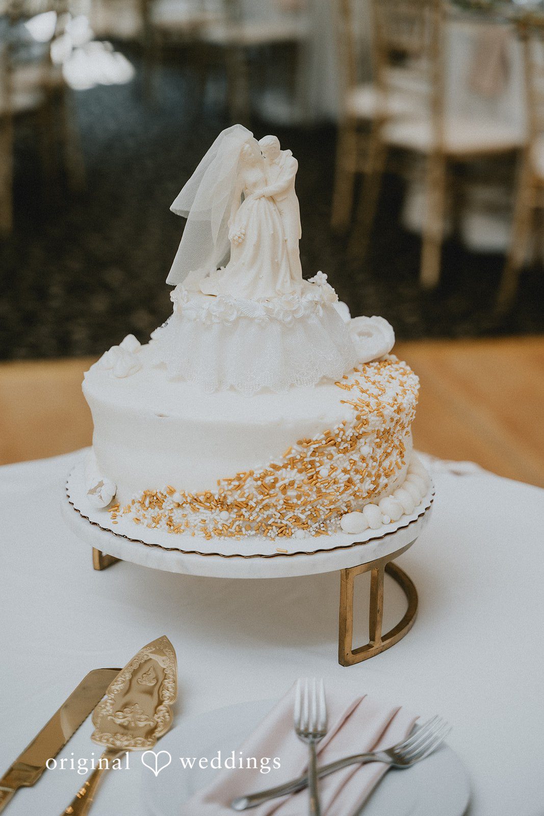 Carly + Dillon A multi-tiered white wedding cake decorated with flowers sitting on a table.