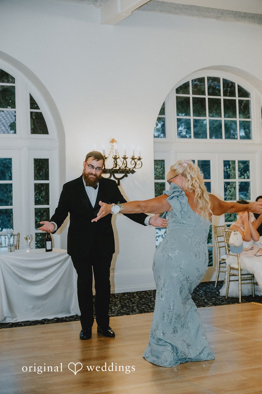 Carly + Dillon A man and woman in formal attire laughing and dancing at a wedding reception.