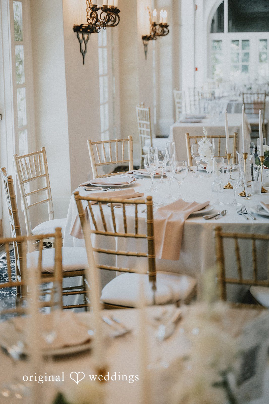Carly + Dillon A close-up view of a set wedding reception table decorated with glassware and white linens.