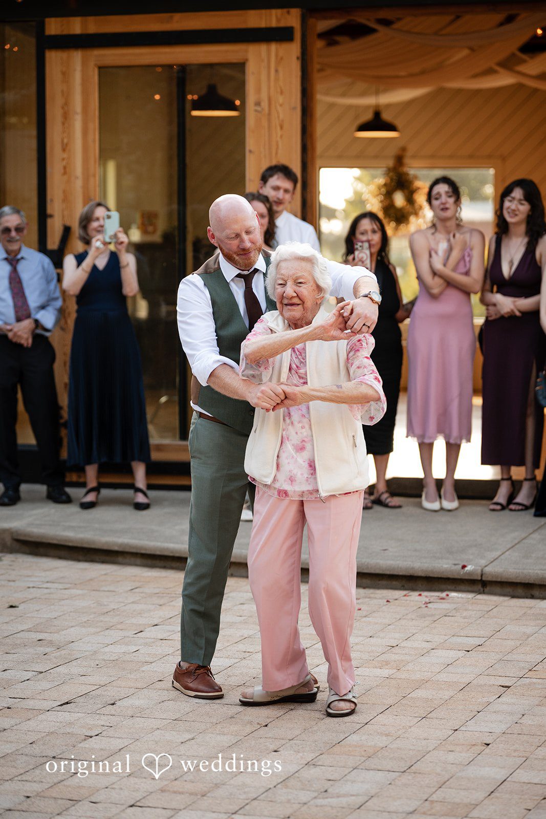 Victoria + Skyler Elderly woman dancing on a patio surrounded by wedding guests.
