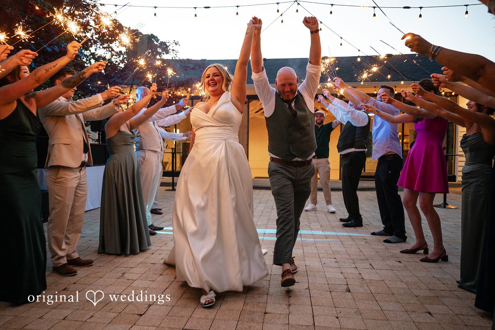 Victoria + Skyler Bride and groom walking through a crowd of wedding guests holding sparklers.