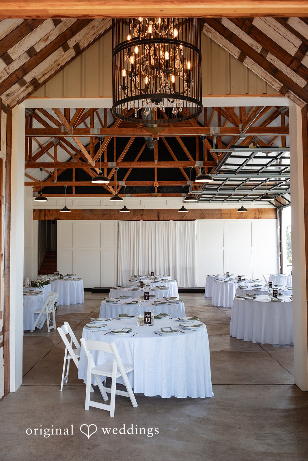 Victoria + Skyler Empty wedding reception venue with white tables and chairs.