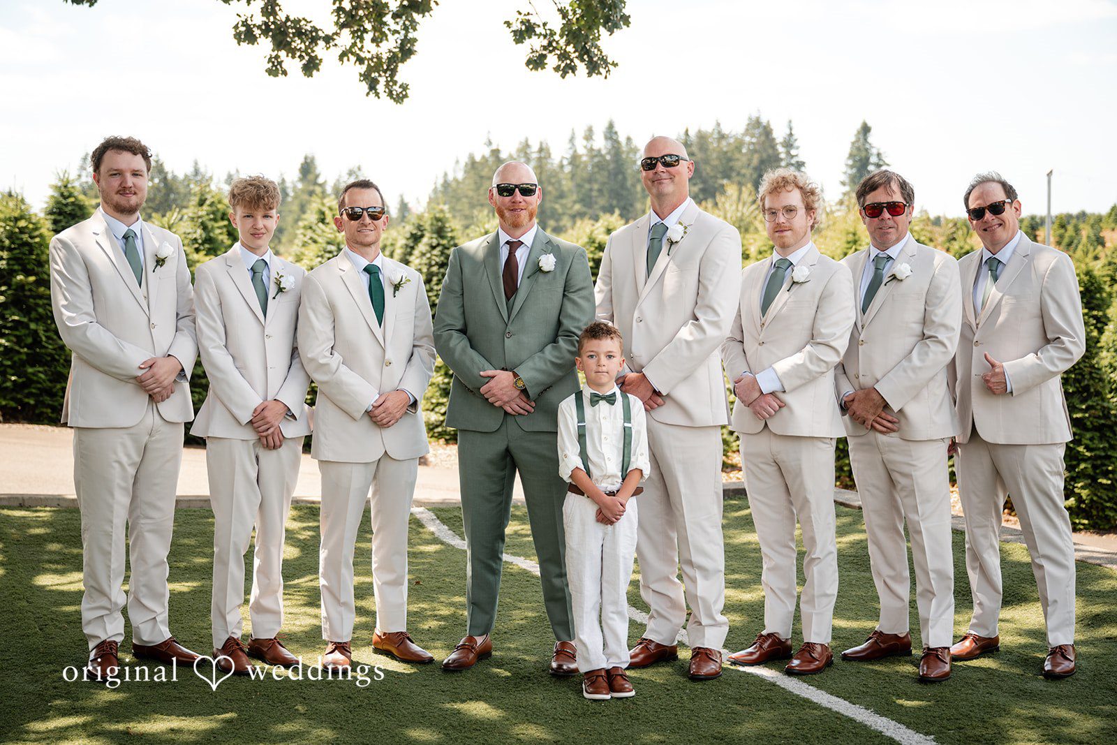 Victoria + Skyler Groom and groomsmen wearing matching light-colored suits standing together.