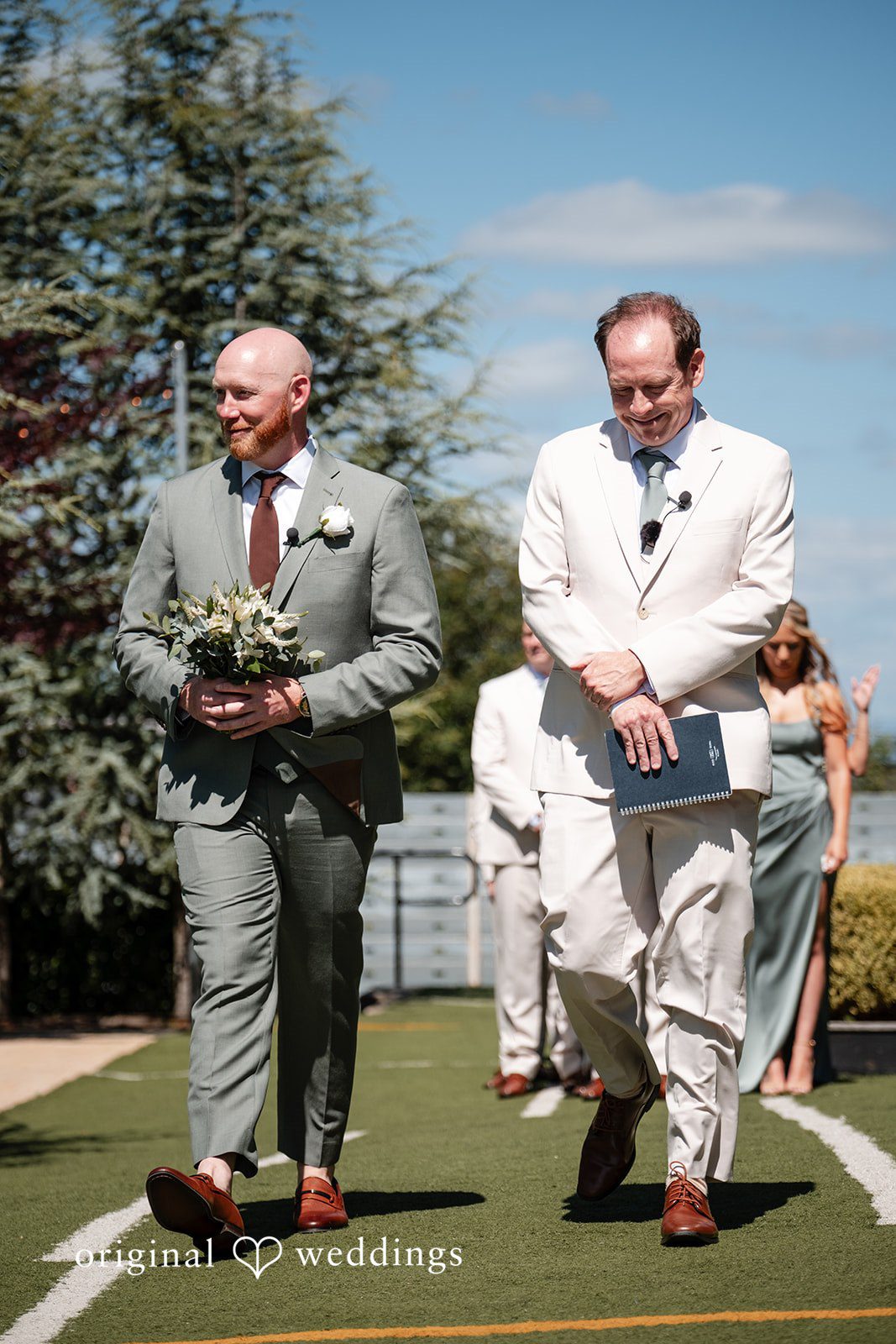 Victoria + Skyler Two men in suits walking down a paved path.