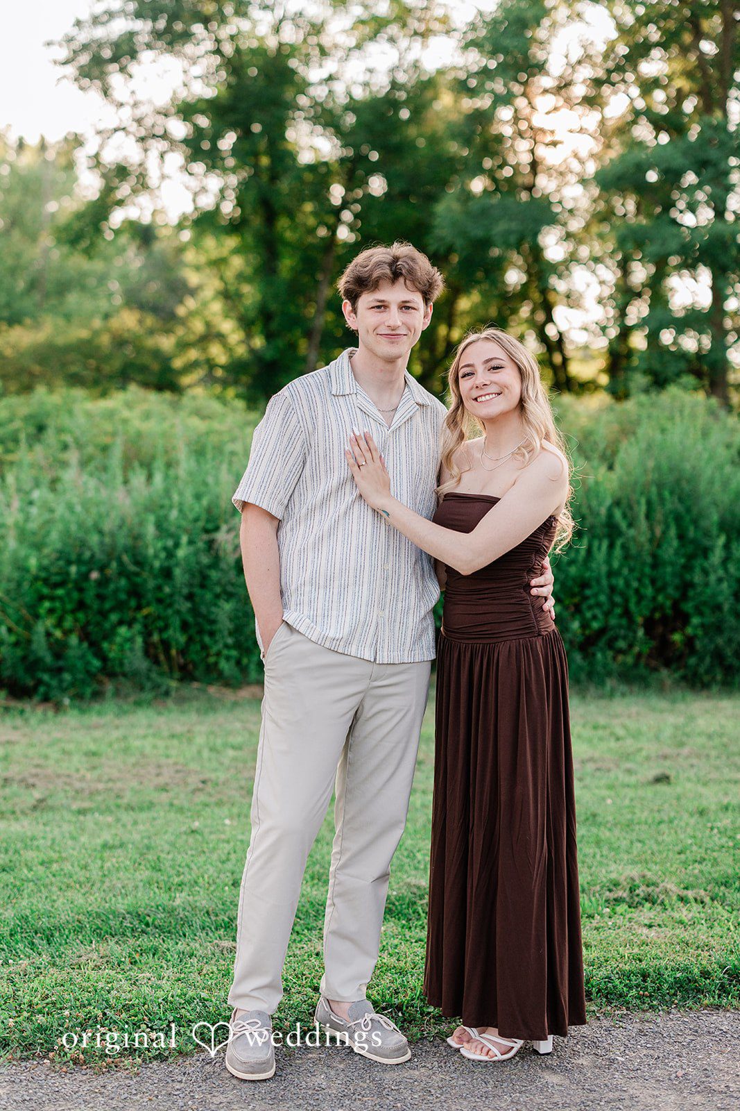 Sara + Jack A distant shot of a couple standing side by side in a lush green field.