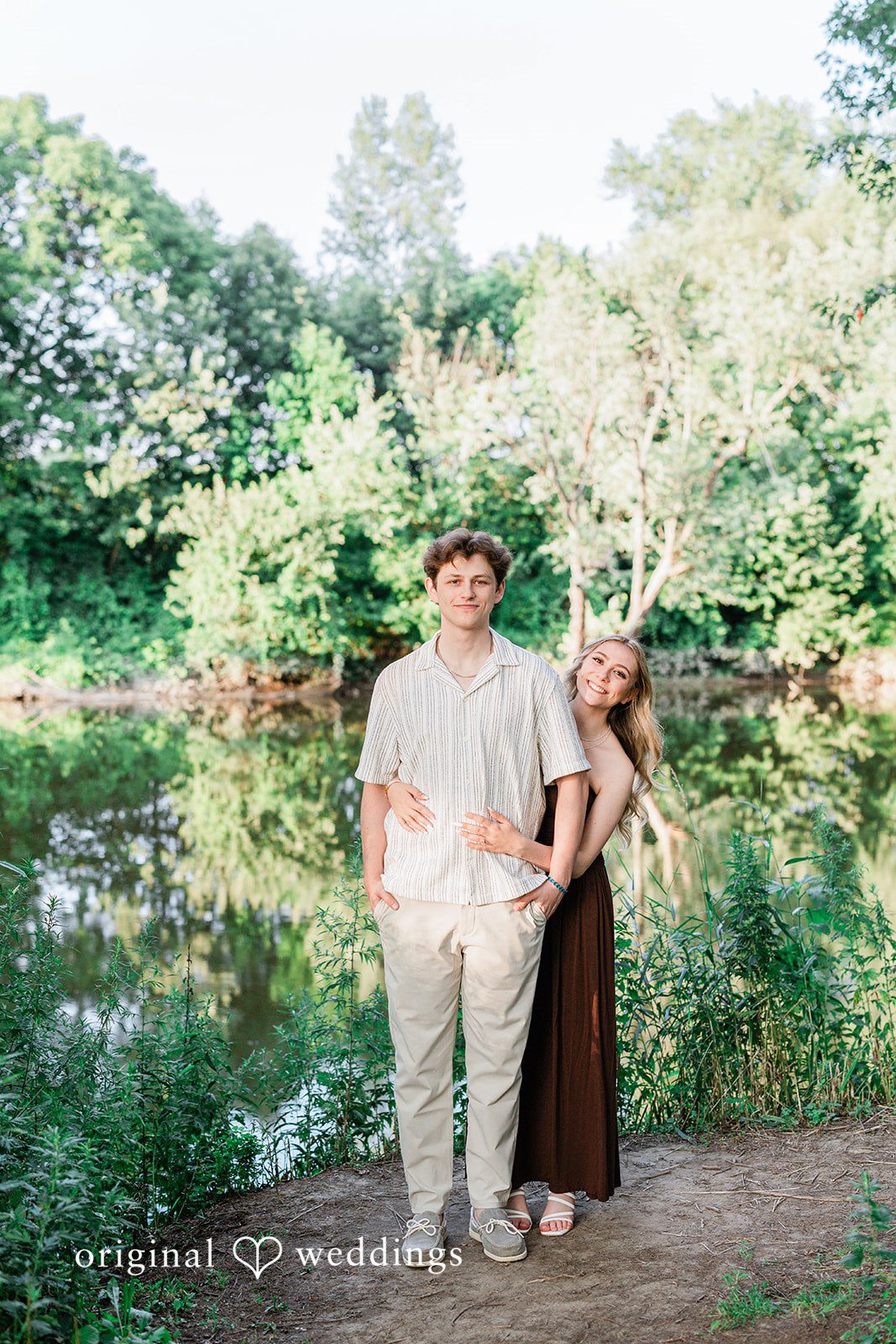 Sara + Jack A couple posing closely together near a pond surrounded by greenery.