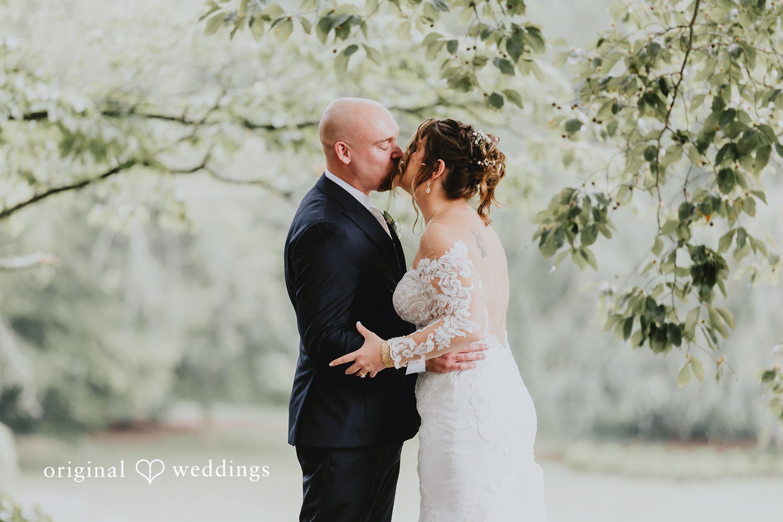 Samantha + Michael Bride and groom embracing and kissing under weeping tree branches.