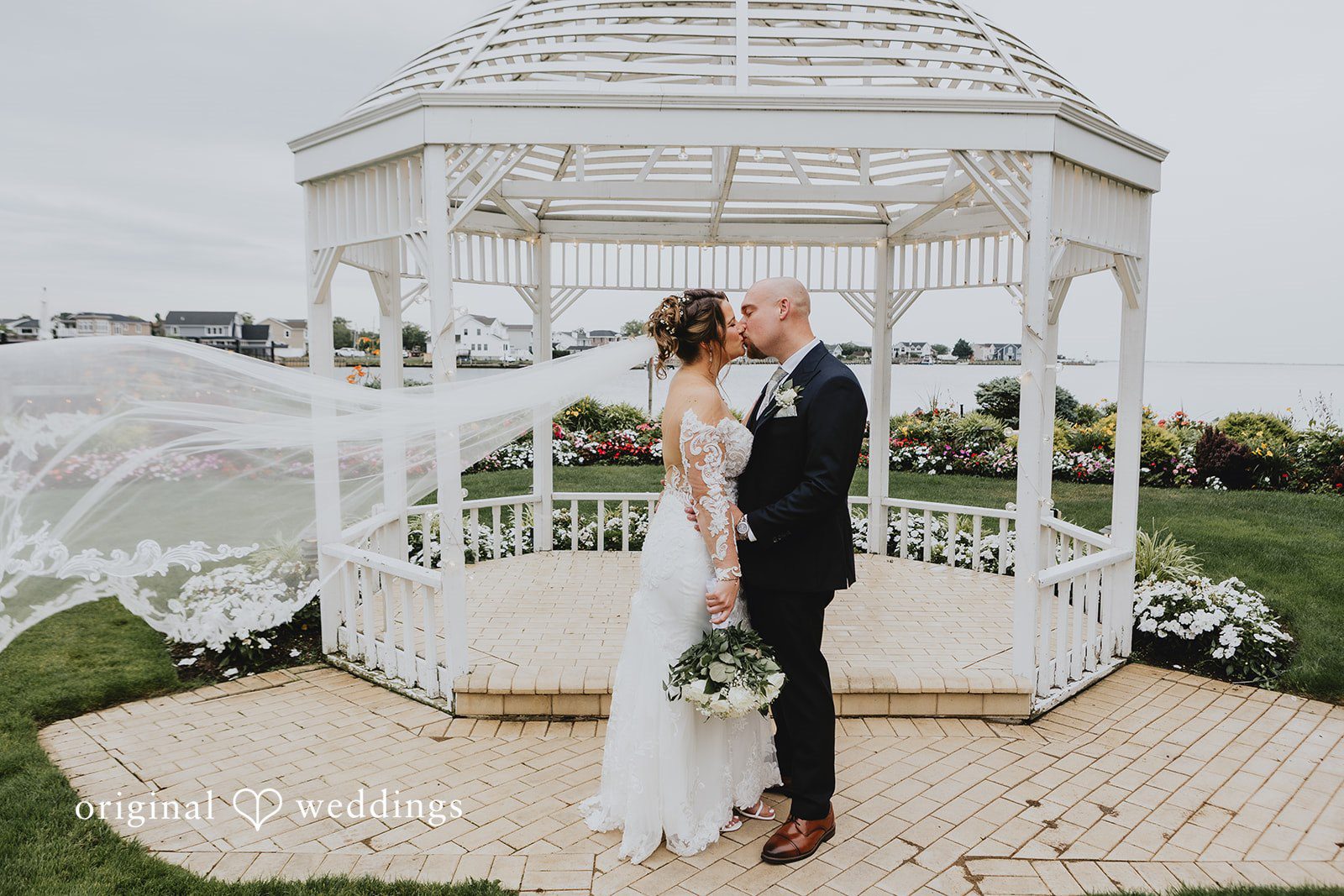 Samantha + Michael Bride and groom kissing in front of a white gazebo.