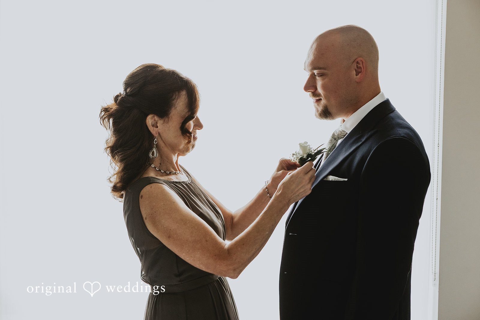 Samantha + Michael Women adjusting the lapel of a groom's tuxedo jacket.