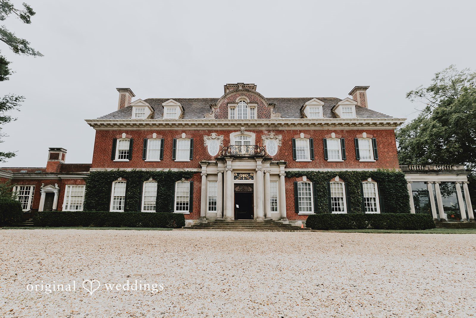 Samantha + Michael Grand brick mansion estate with a wide gravel driveway.