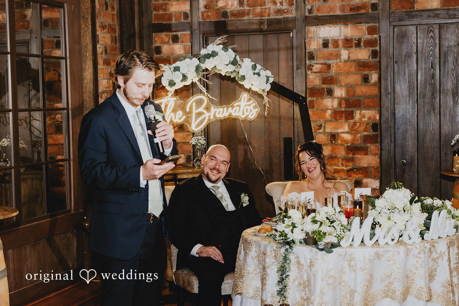 Samantha + Michael Groom standing by a brick wall during reception speeches.