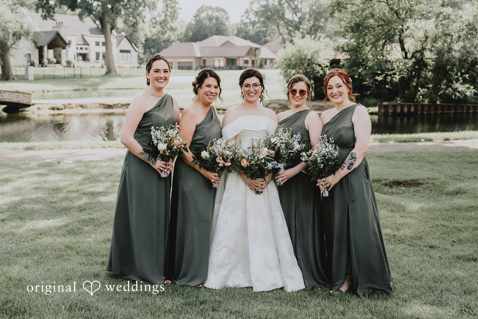 Brandon + Natalie A bride and bridesmaids in dark gowns holding bouquets in a park.