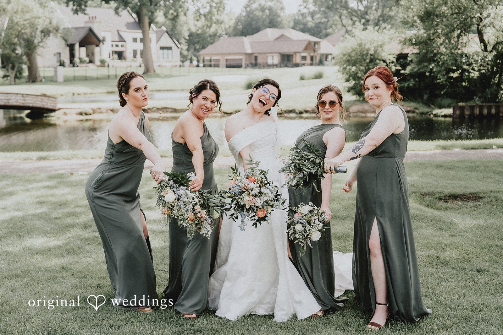 Brandon + Natalie A bride standing with bridesmaids in dark green dresses near a body of water.