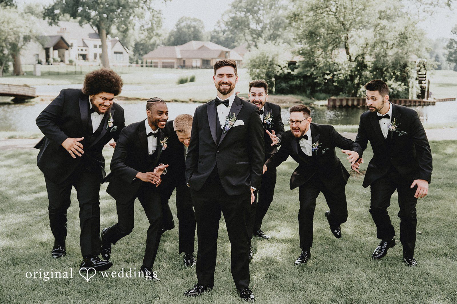 Brandon + Natalie A groom and groomsmen laughing and posing dynamically near trees.