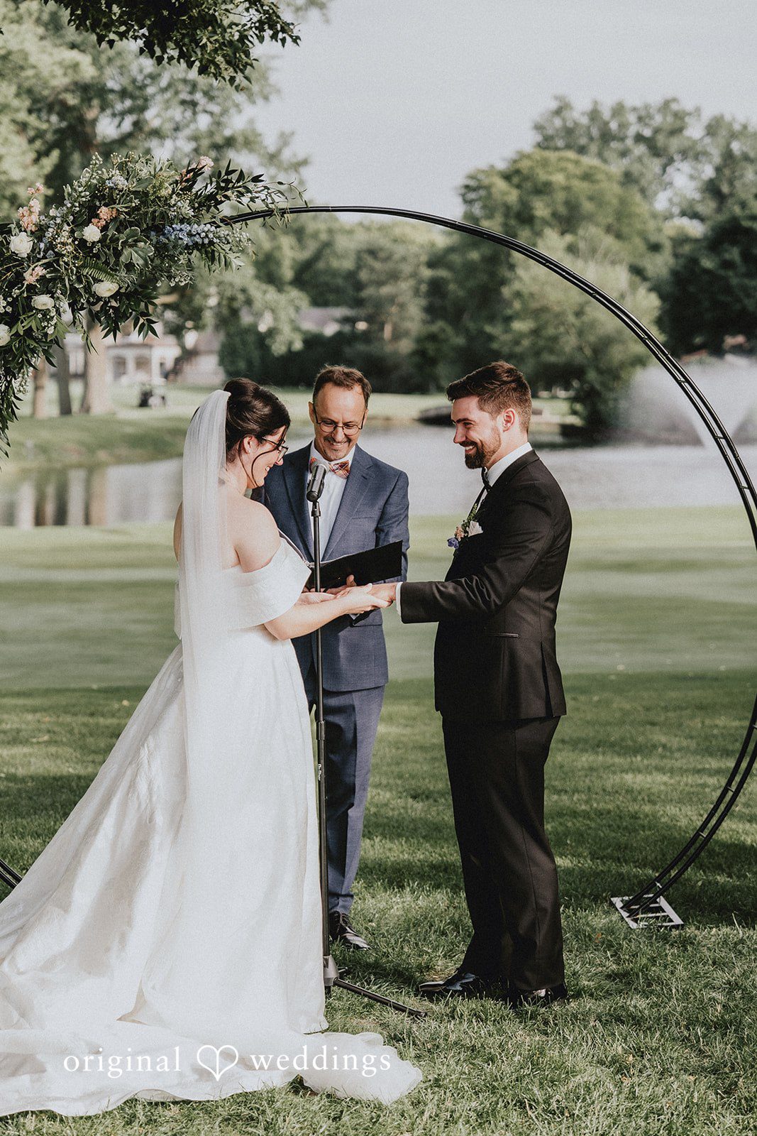 Brandon + Natalie A bride and groom standing hand-in-hand in front of a circular arch.