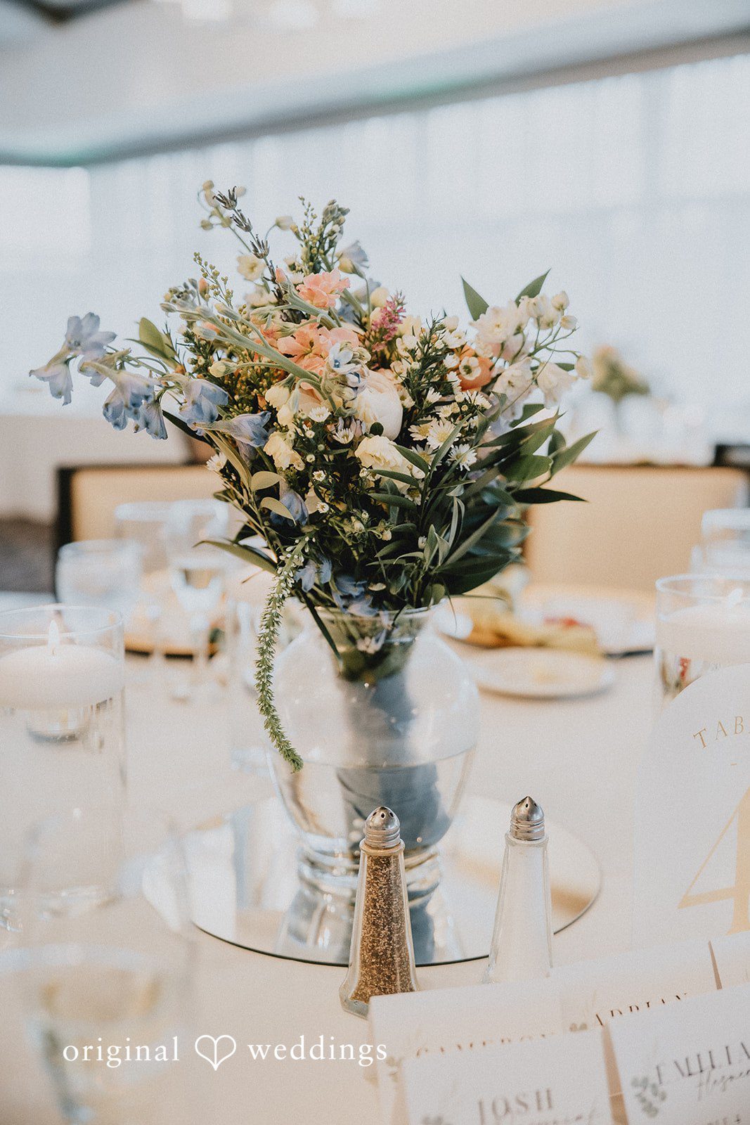 Brandon + Natalie A floral centerpiece on a table set with wine glasses and plates.
