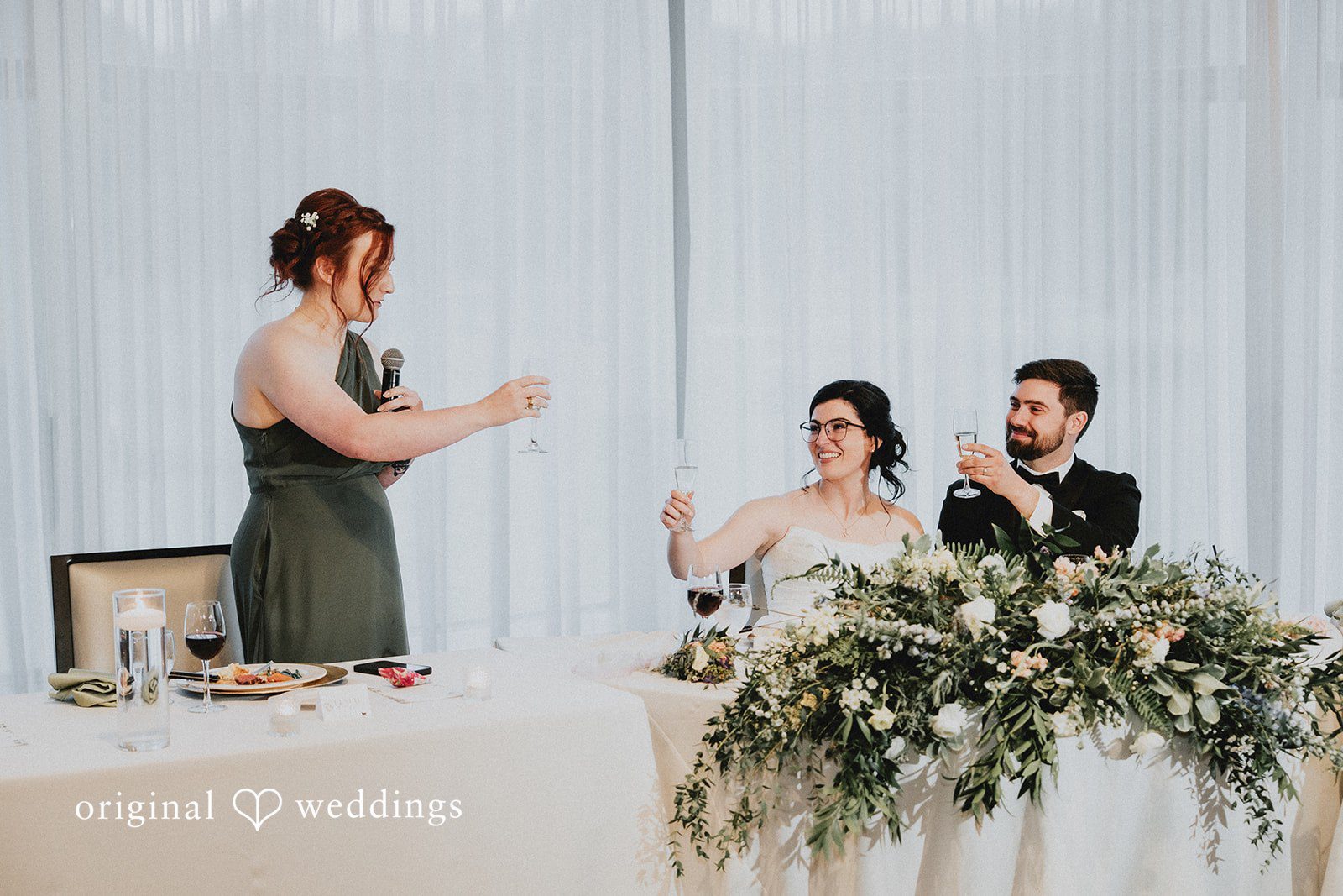 Brandon + Natalie Wedding guests giving a toast at a decorated reception head table.