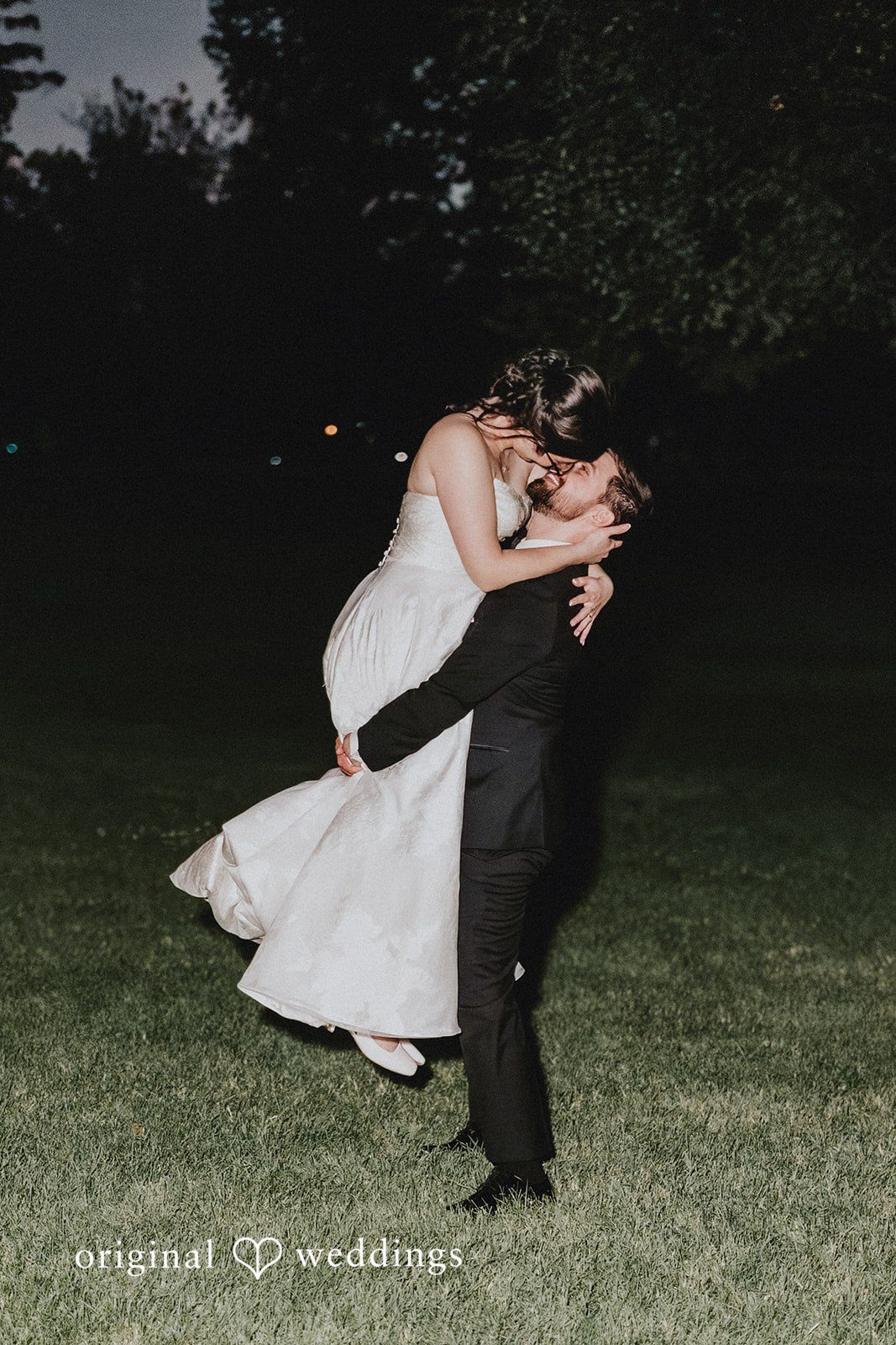 Brandon + Natalie A groom dipping a bride during a dance on a lawn at night.