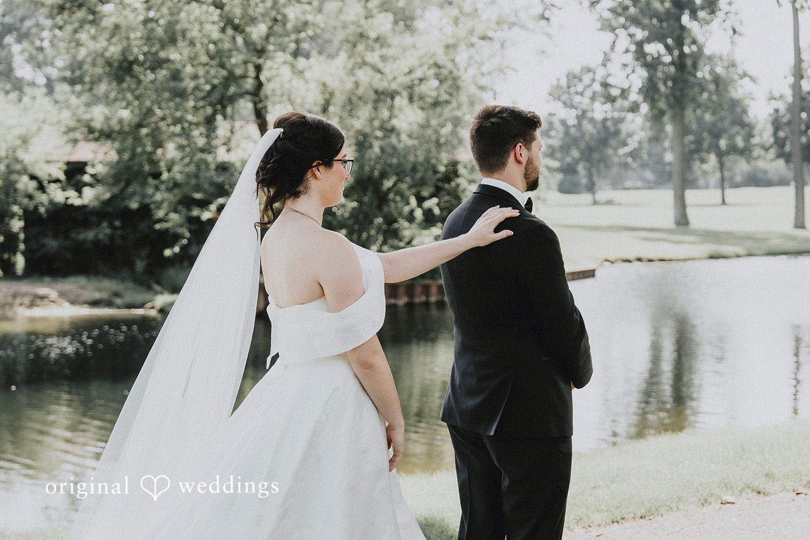 Brandon + Natalie A bride approaching a groom from behind next to a lake.