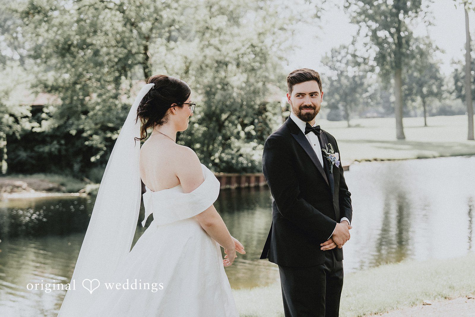 Brandon + Natalie A bride and groom standing facing each other near a scenic waterfront.