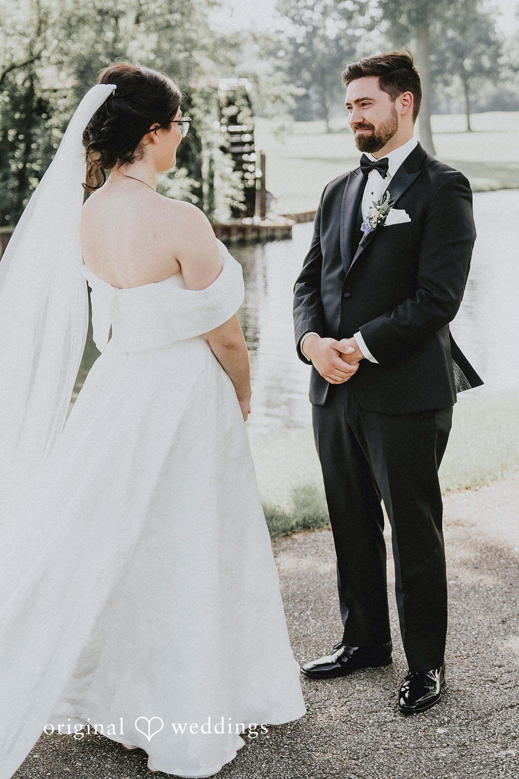 Brandon + Natalie A bride and groom smiling and looking at each other near water.