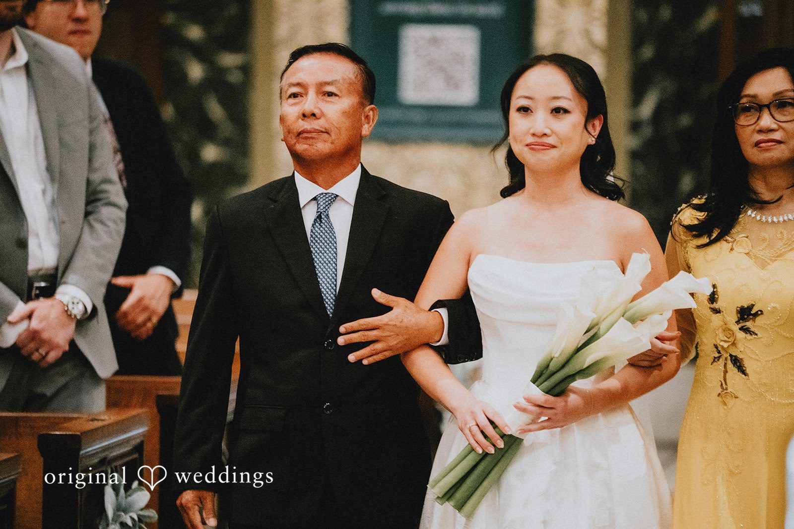 Aleksandar + Anna A bride walking down the aisle while holding a bouquet next to an older man.