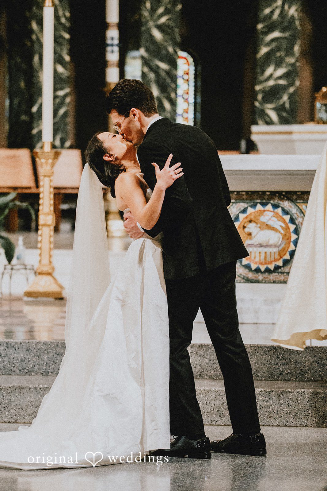Aleksandar + Anna A bride and groom sharing a romantic kiss at the altar.