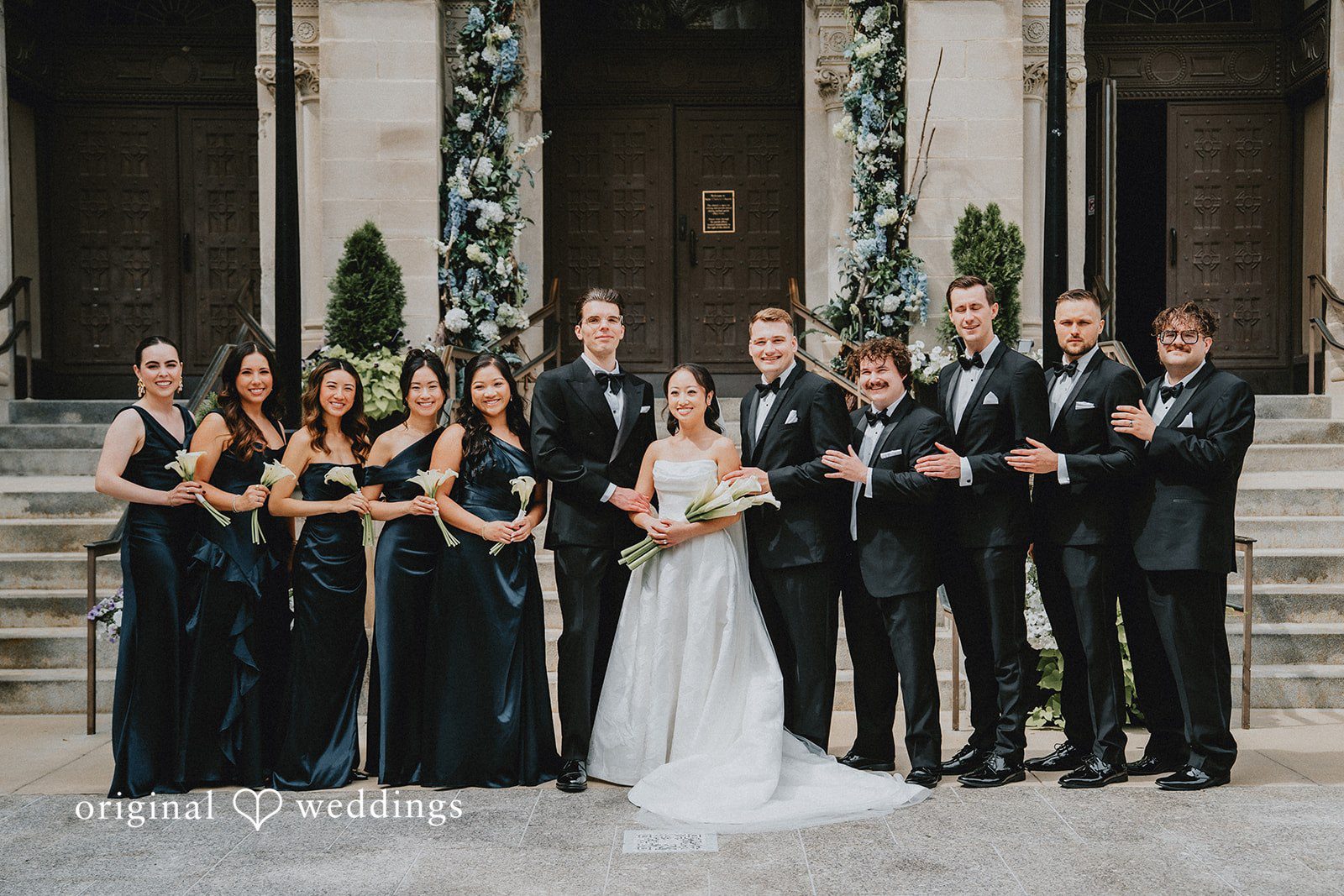 Aleksandar + Anna A full wedding party including bridesmaids and groomsmen posing together on stone steps.