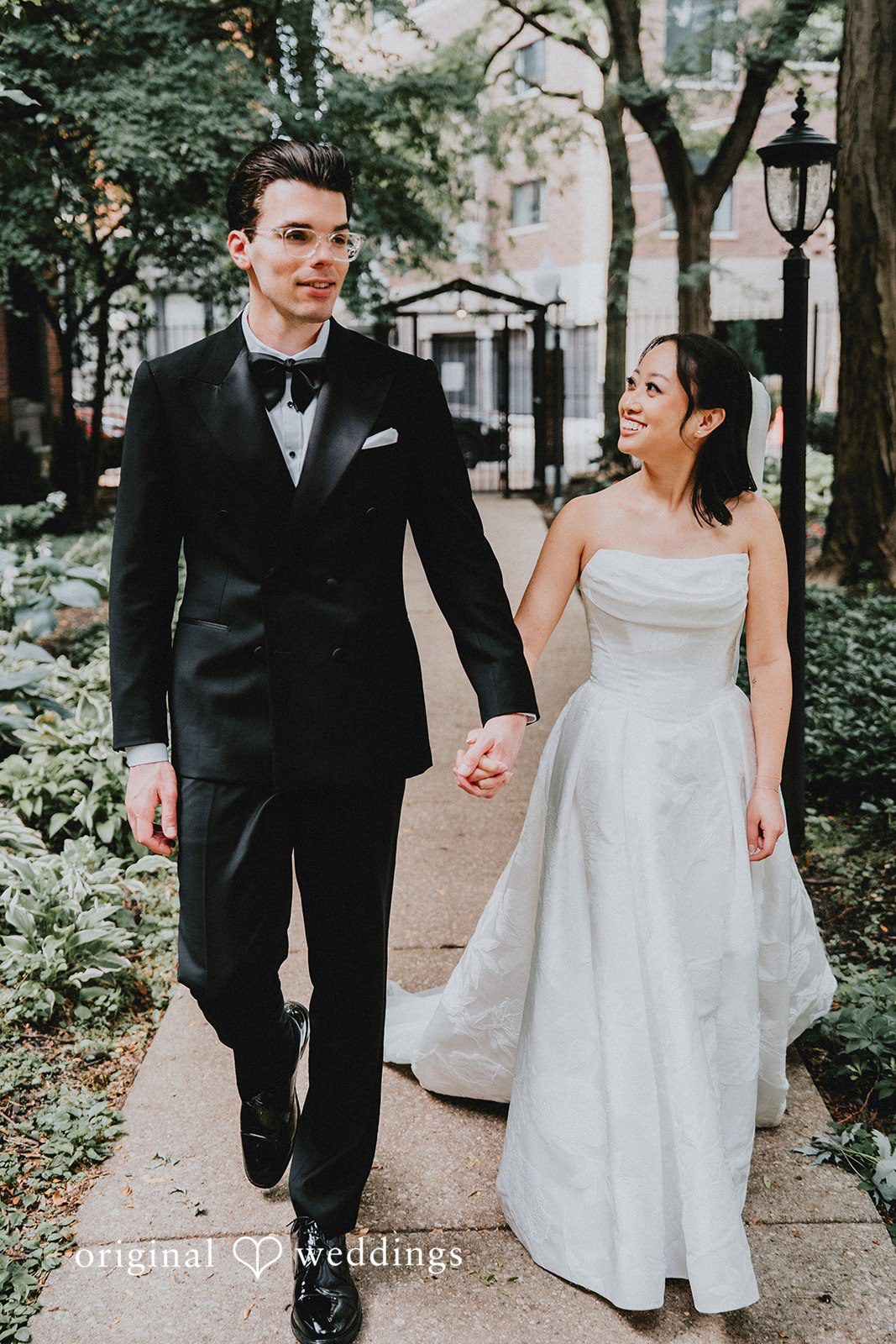 Aleksandar + Anna A bride and groom smiling and holding hands while walking together.