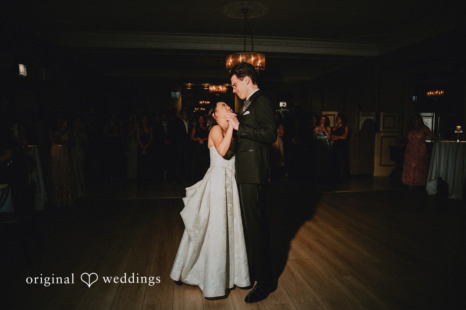 Aleksandar + Anna A bride and groom sharing their first dance in a softly lit reception hall.