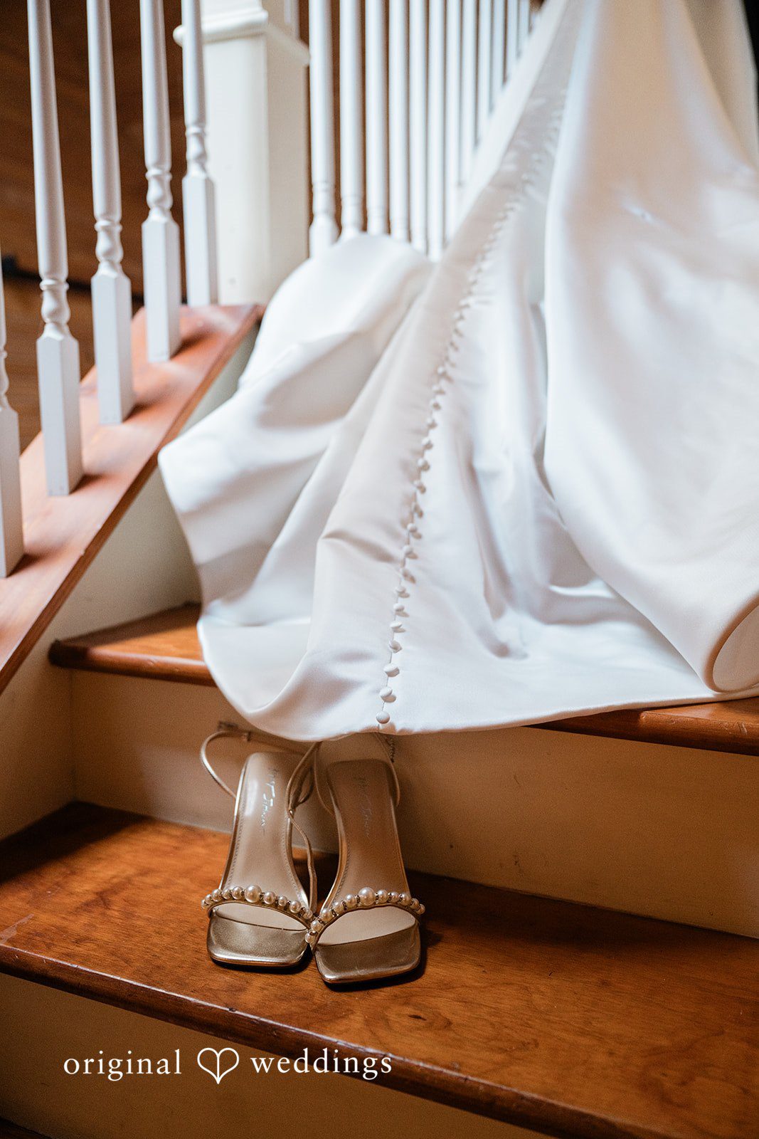 Lauren + Brinton The bottom hem of a long white dress and sandaled feet on wooden steps.