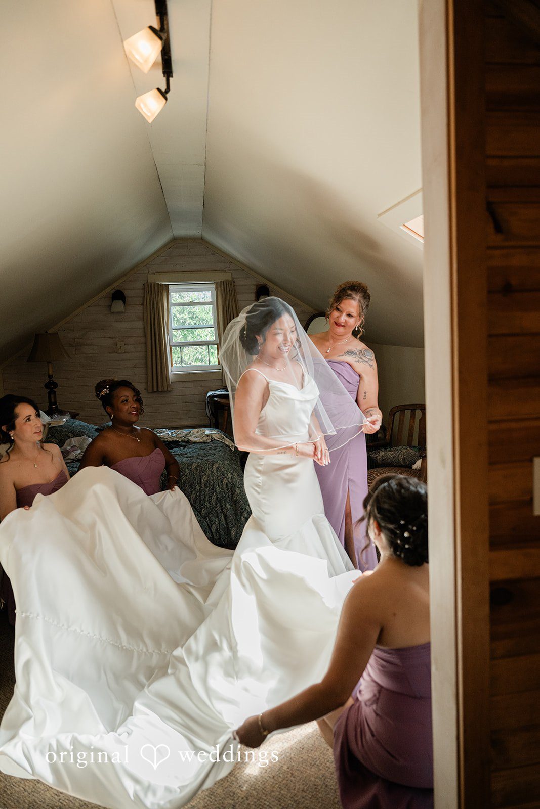 Lauren + Brinton A bride having the train of her white wedding dress adjusted by others.