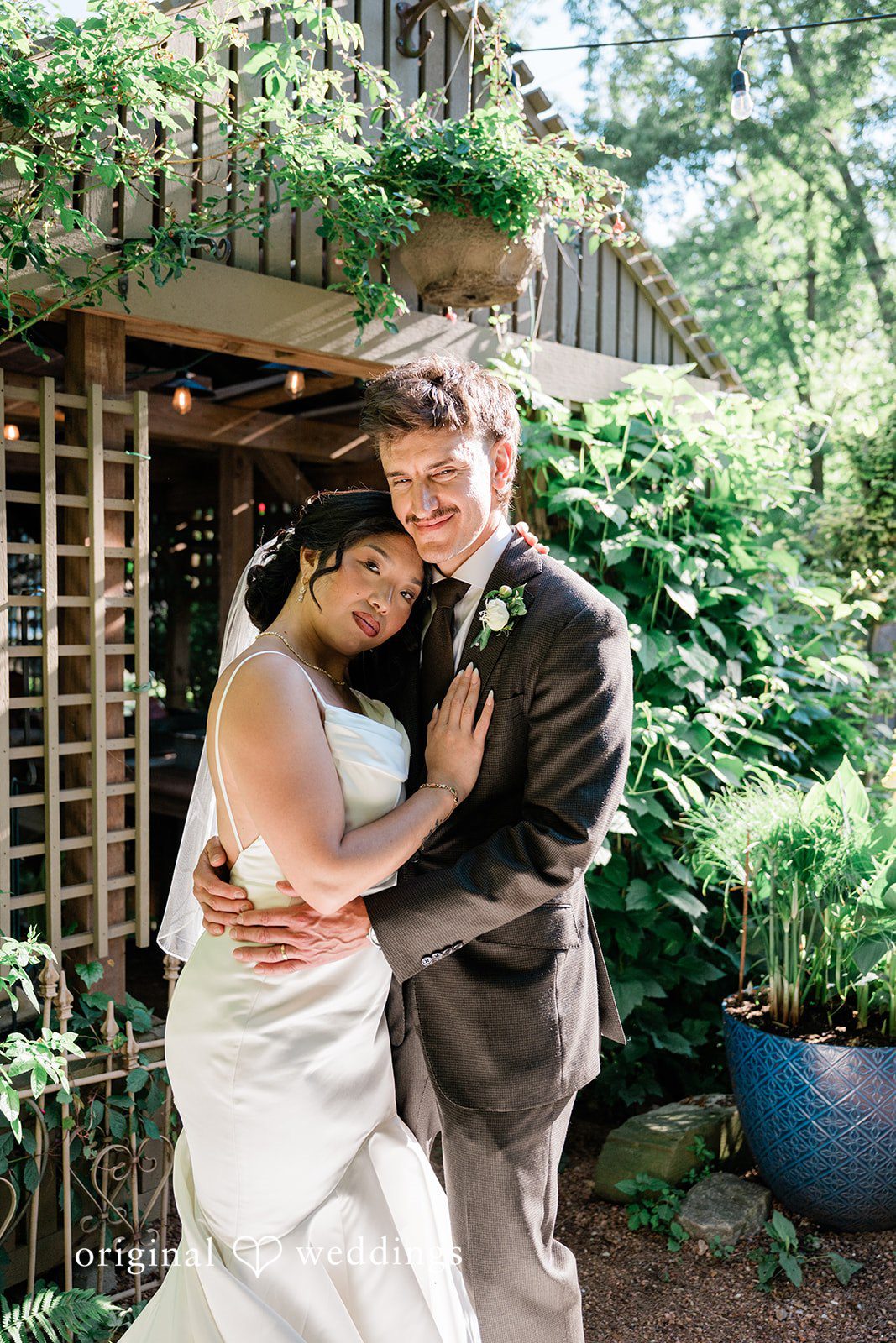 Lauren + Brinton A bride and groom embracing closely near a wooden structure.
