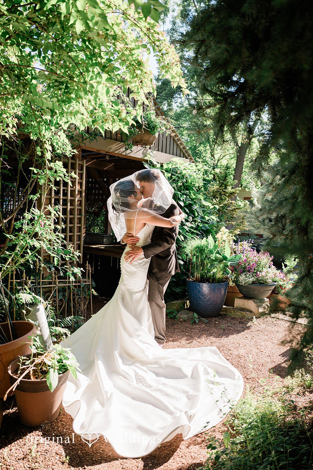Lauren + Brinton A bride and groom sharing a kiss in a lush green garden.