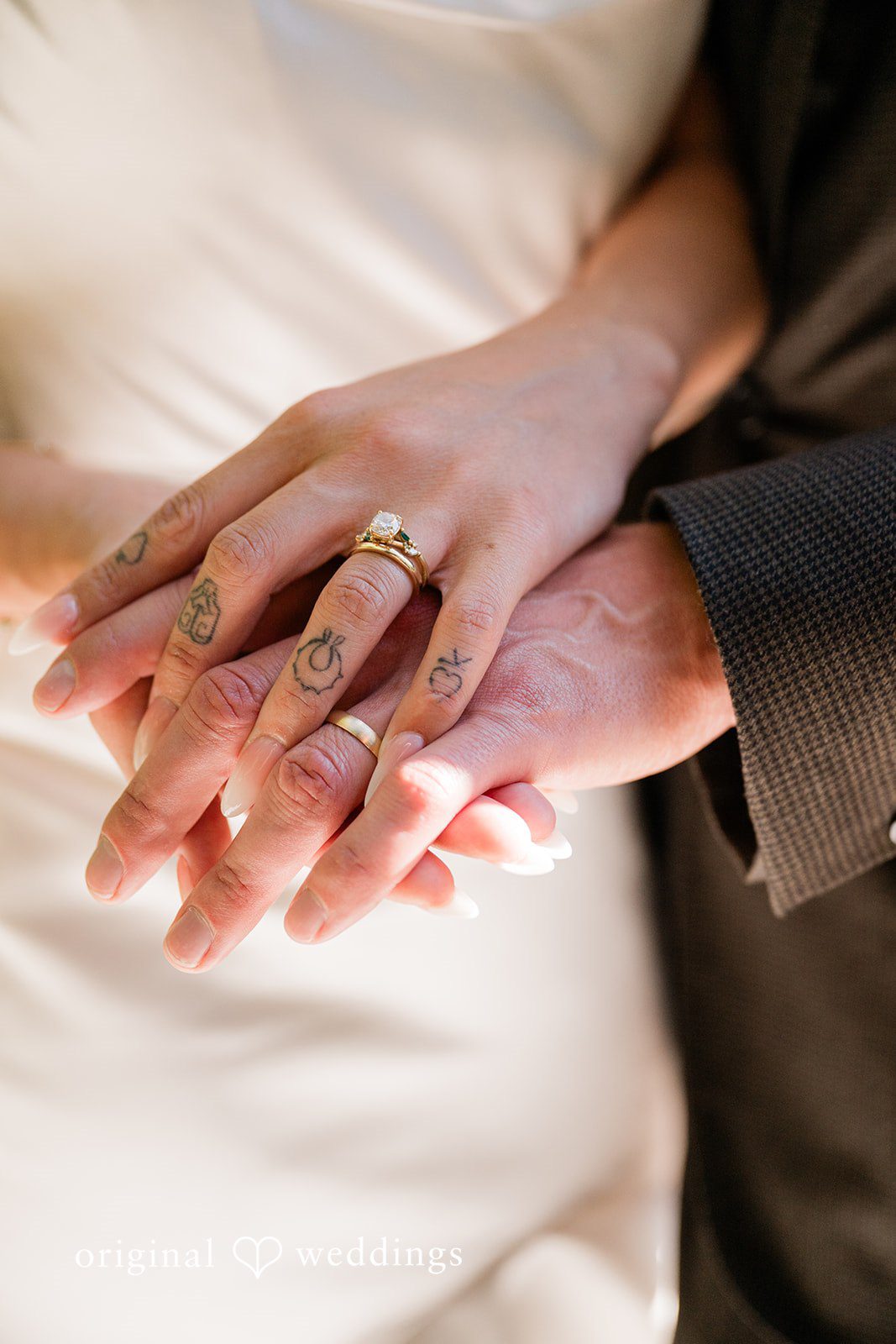 Lauren + Brinton Close-up of two people holding hands, showcasing wedding rings on their fingers.