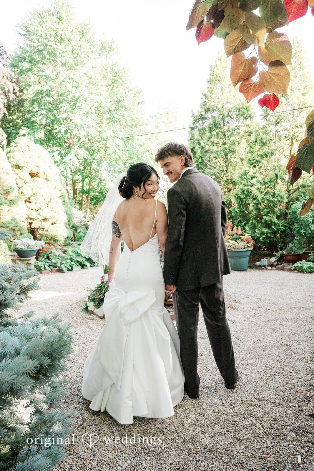 Lauren + Brinton A bride and groom posing together closely in front of a rustic backdrop.