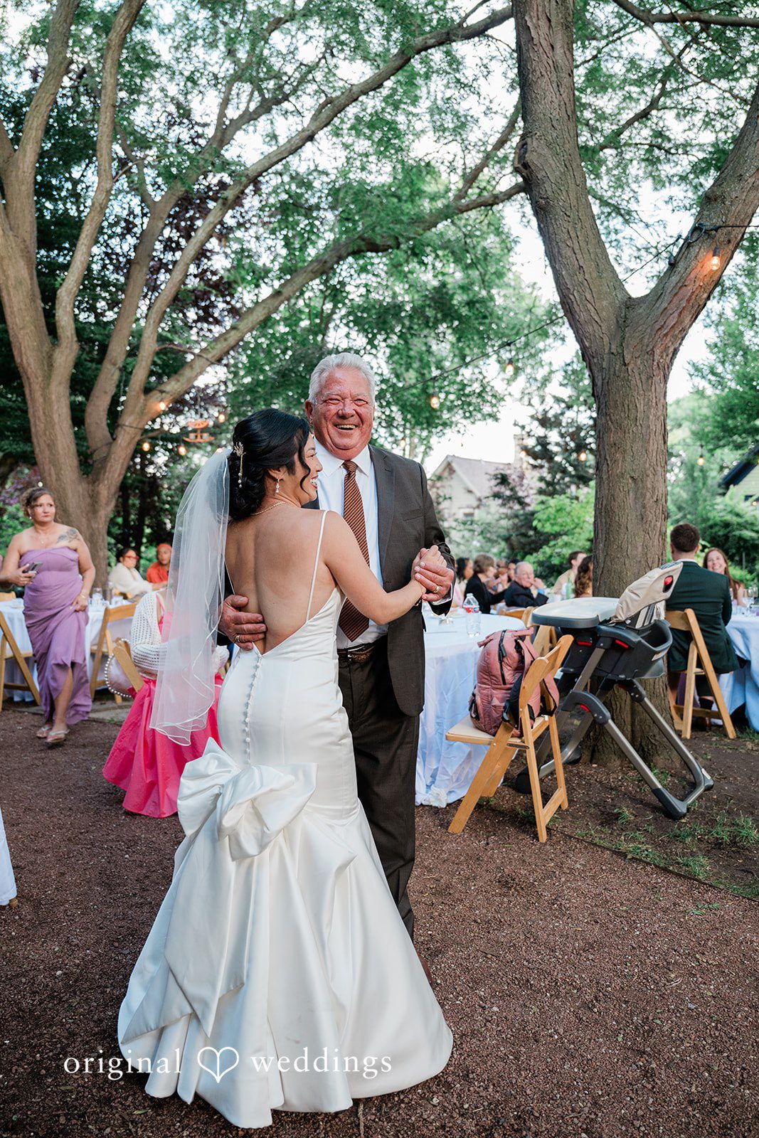 Lauren + Brinton A bride dancing with a man under trees at an event.