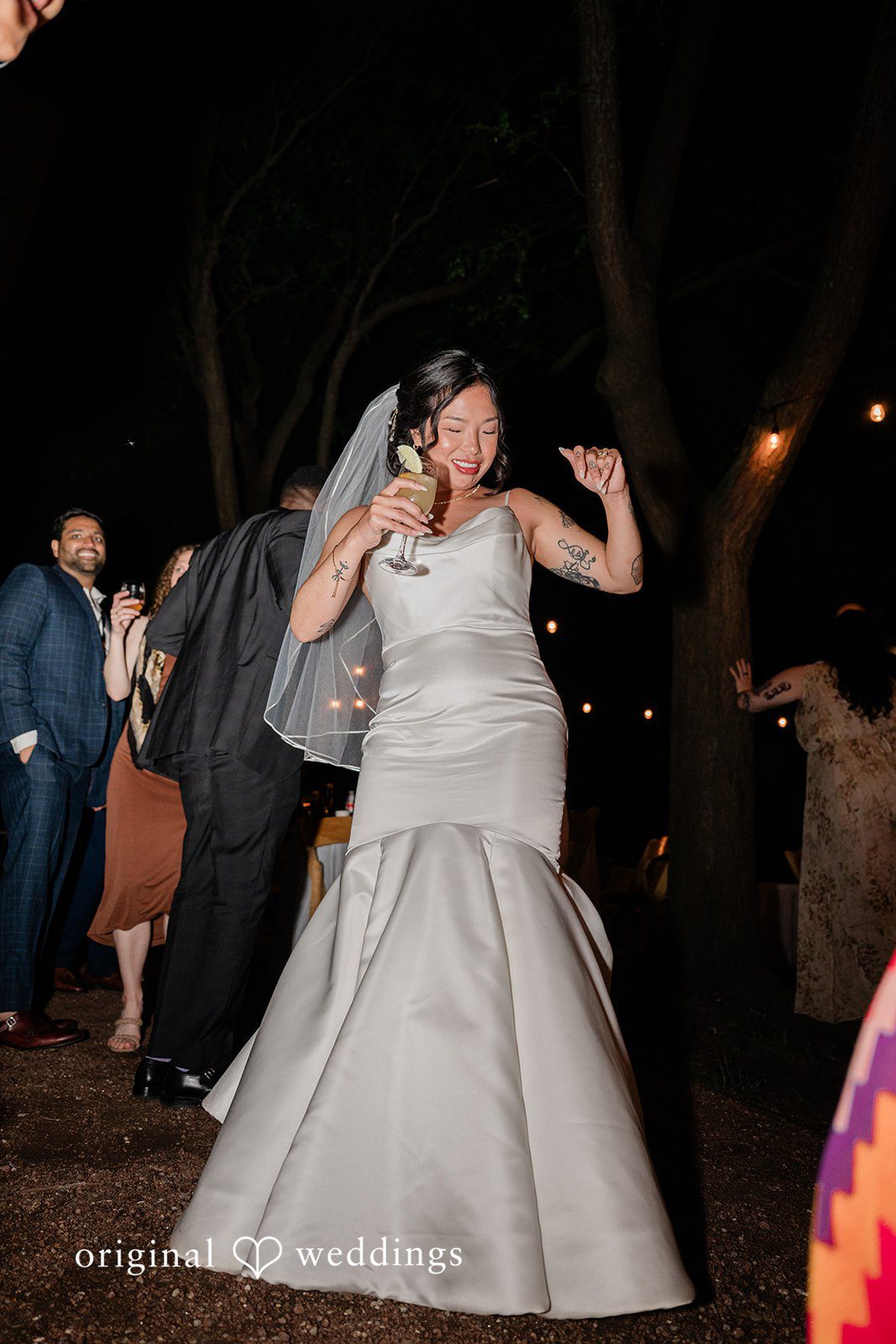 Lauren + Brinton A bride enthusiastically dancing at an evening reception.