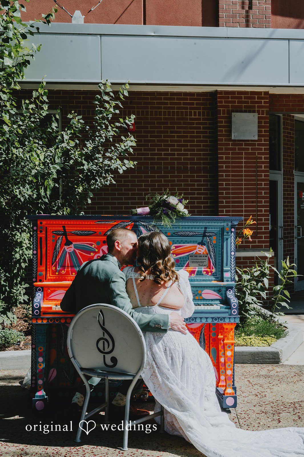 Elizabeth + Willis Bride and groom embracing while seated at a vibrantly painted piano.