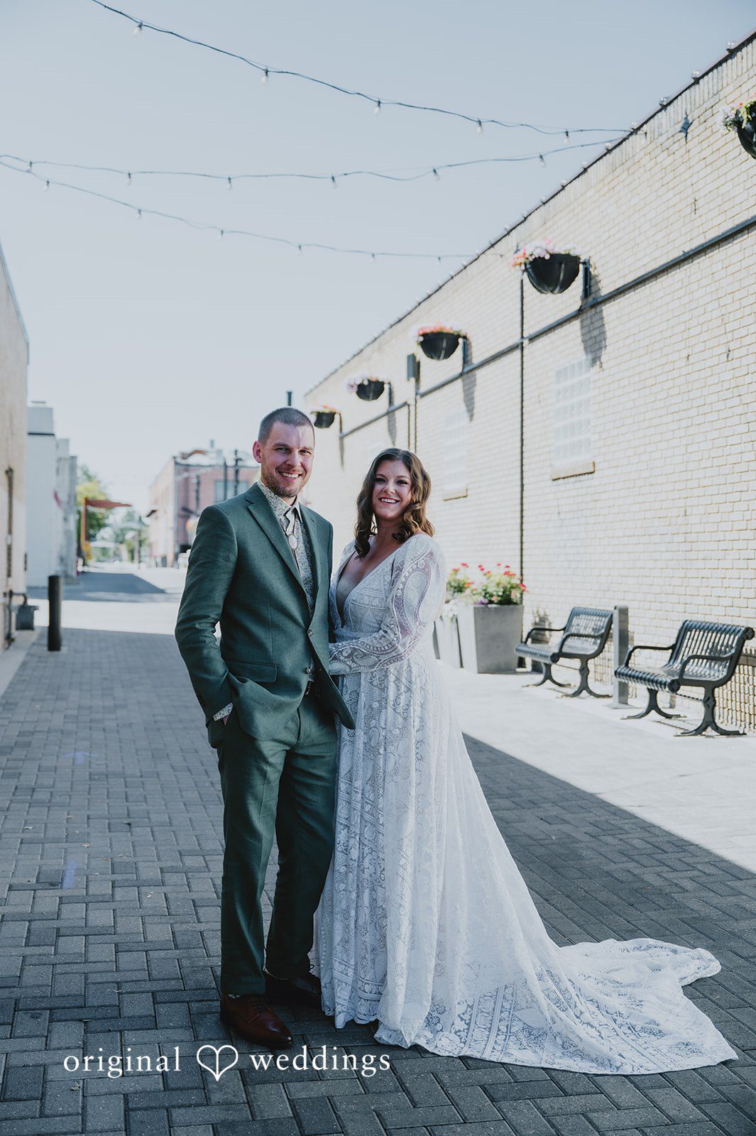 Elizabeth + Willis Couple standing hand-in-hand on a paved pathway between buildings.